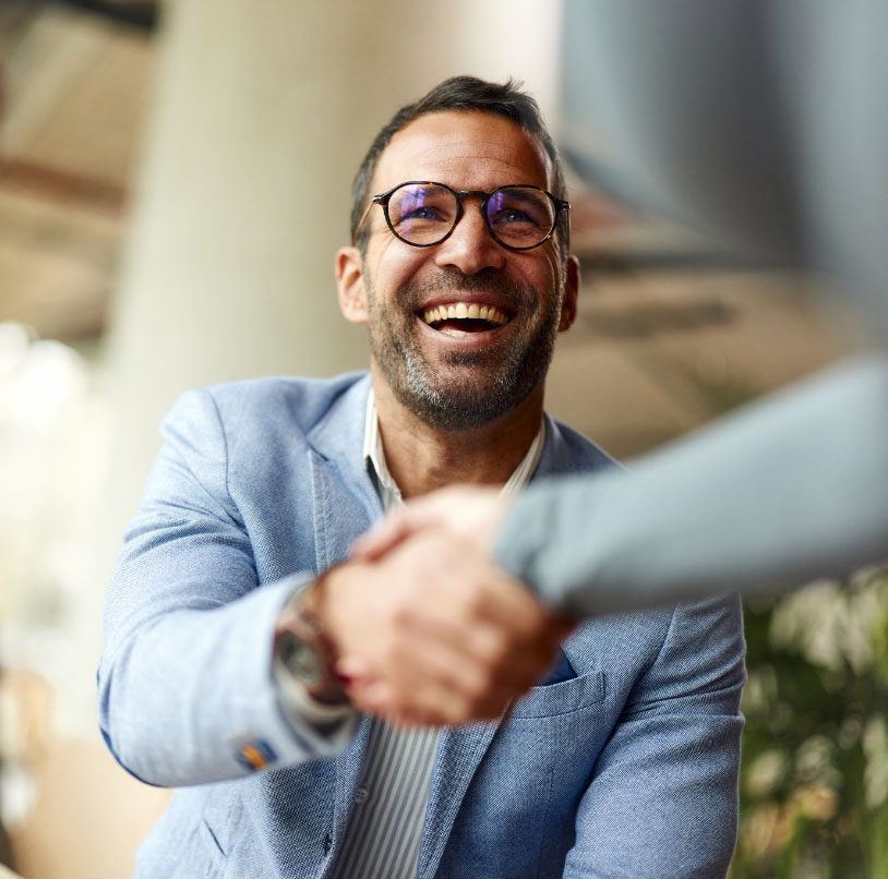 Un homme souriant serre la main à quelqu'un.