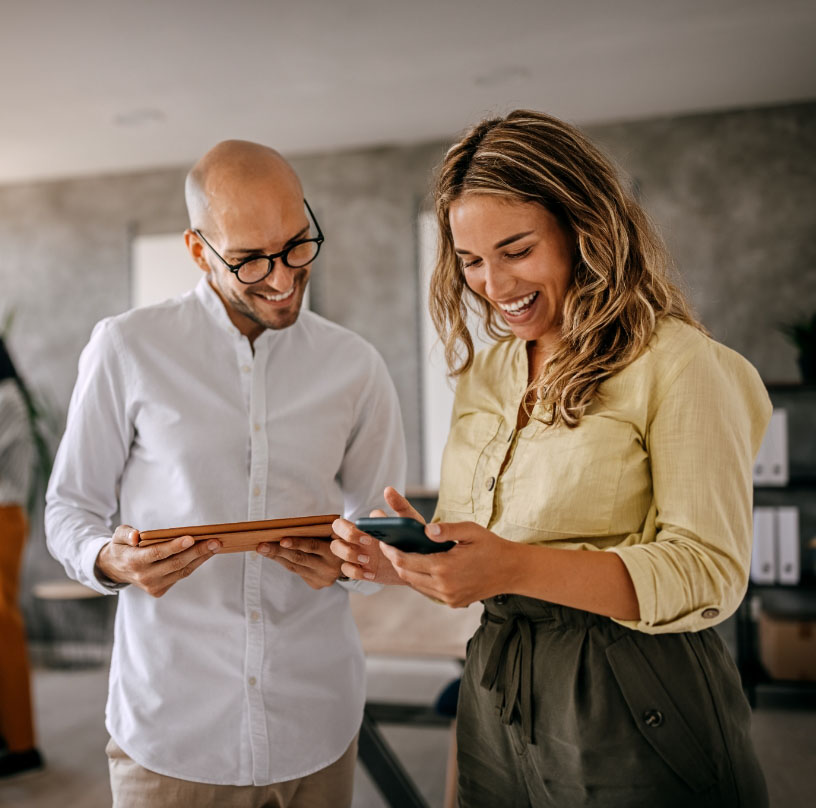 Une homme et une femme dans un bureau qui regarde une tablette.